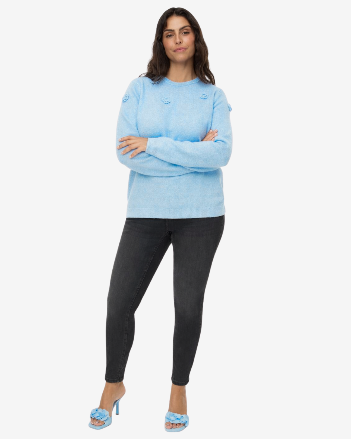 Woman wearing a light blue sweater and black pants on a white background