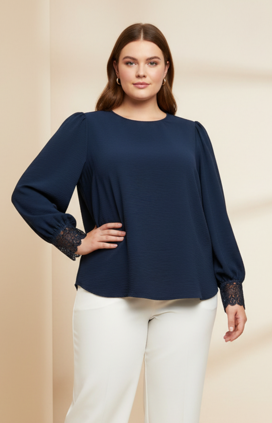 Woman wearing a navy blue blouse with lace cuffs on a beige background
