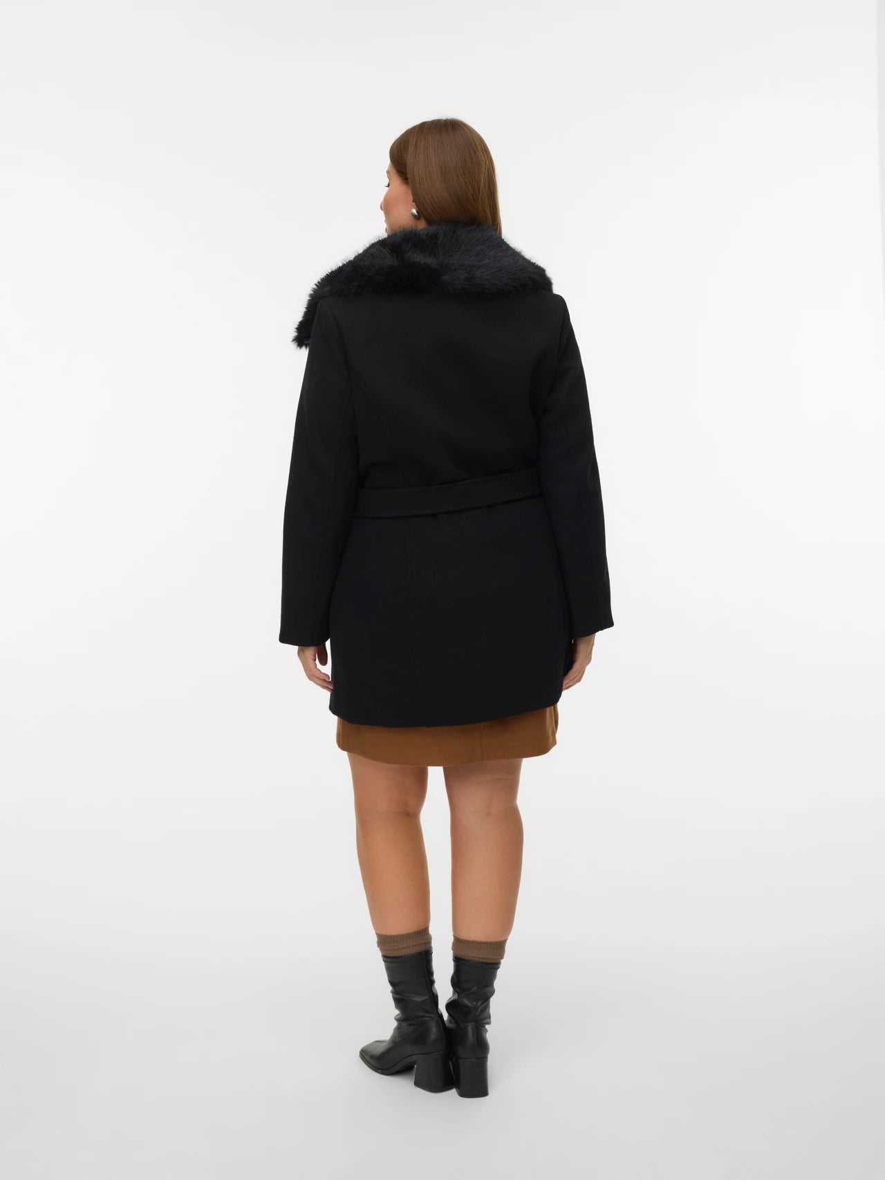 Person wearing a black coat with fur collar on a white background