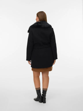 Person wearing a black coat with fur collar on a white background