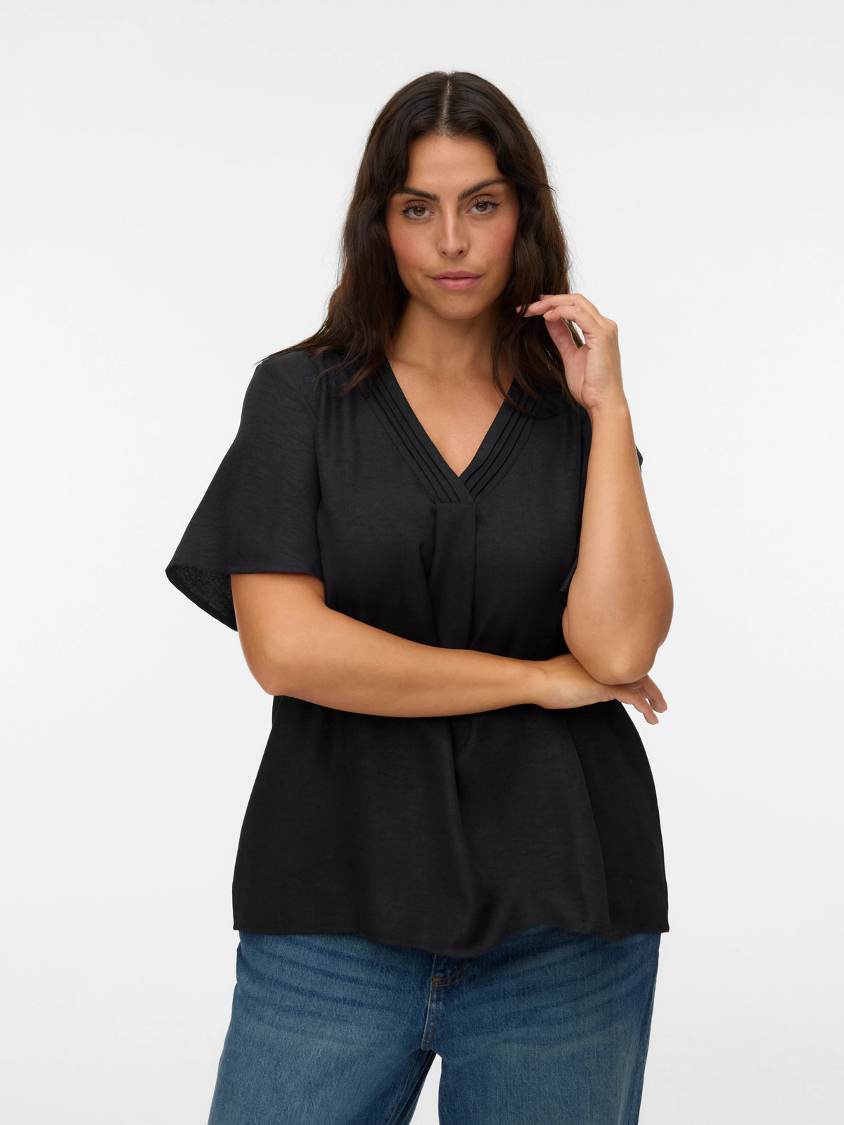 Woman wearing a black top and blue jeans on a white background