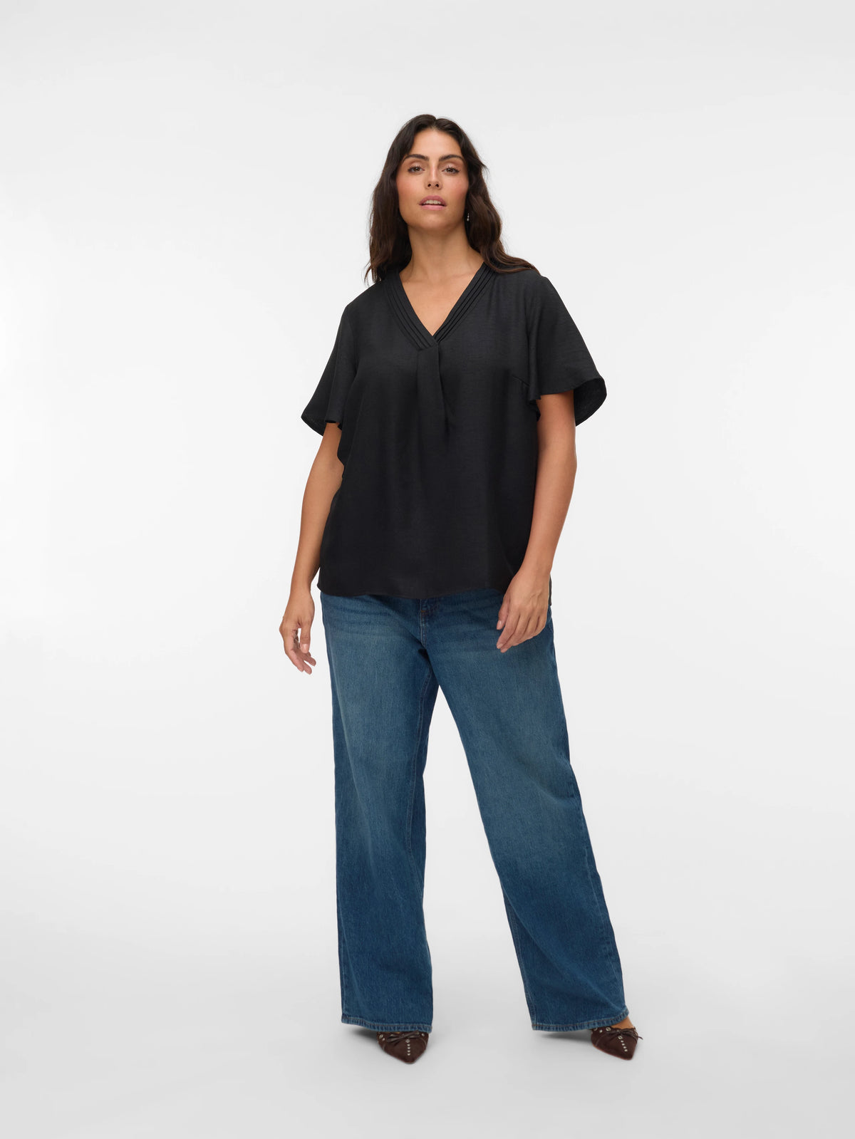 Woman wearing a black top and blue jeans on a white background