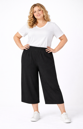 Woman wearing a white t-shirt and black wide-leg pants on a white background