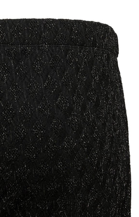 Close-up of the Vero Moda Curve Kali Trousers in Black, a black textured fabric with a subtle diamond pattern and fine shimmering threads, shown against a white background.