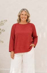 Woman wearing a red top and white pants against a neutral background