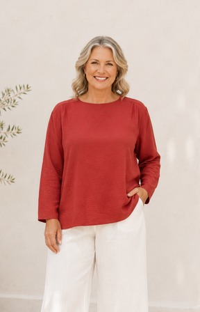 Woman wearing a red top and white pants against a neutral background