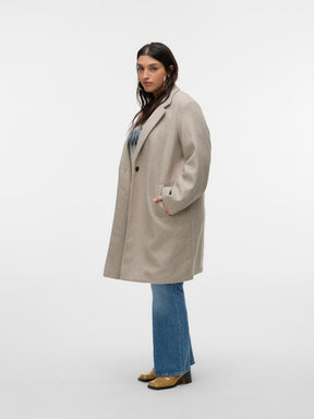 Person wearing a beige coat and blue jeans on a white background