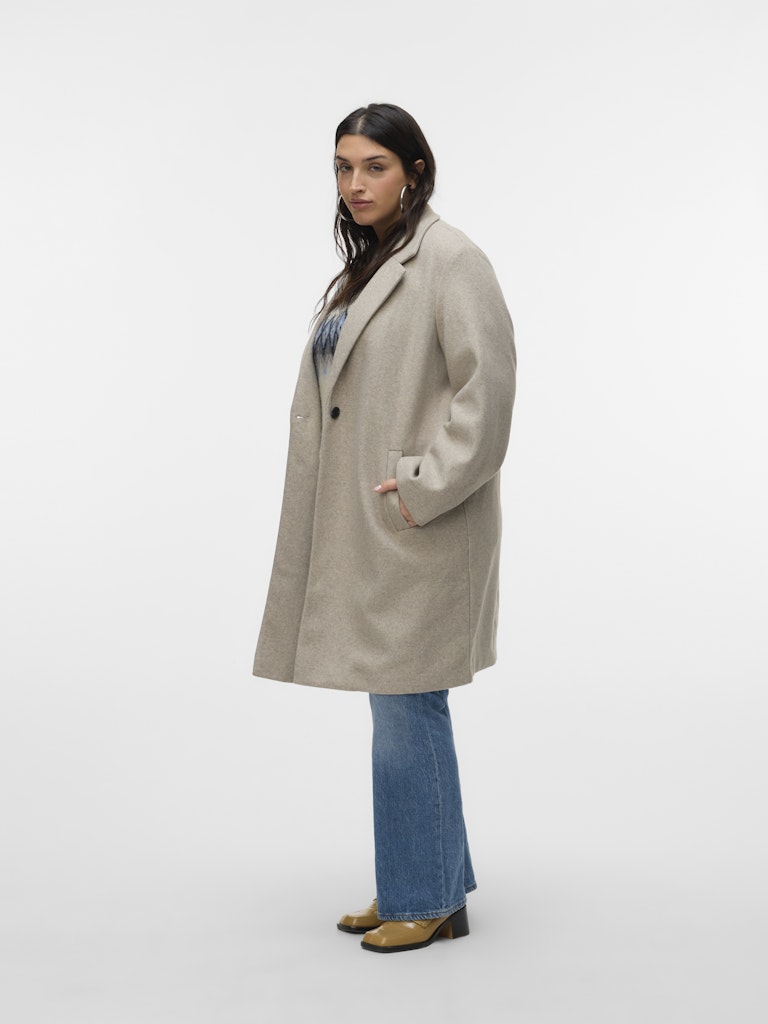 Person wearing a beige coat and blue jeans on a white background