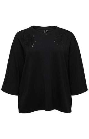 The Vero Moda Curve Nia Top in Black,  black oversized short-sleeve top with floral sequin applique details on the shoulders and sleeves, shown against a plain white background.