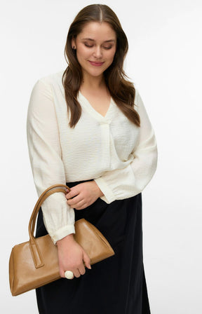 Woman wearing a white blouse with a V neckline and long sleeves, and black skirt holding a brown handbag on a white background