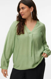 Woman wearing a green blouse with a V neckline, inverted pleat and long sleeves with buttoned cuffs with a plain background