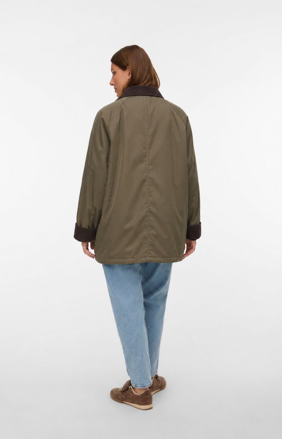 A model shown from the back wearing the Vero Moda Curve Wales Jacket in Grape Leaf, an olive green utility jacket with dark brown collar and cuff trims, paired with light blue jeans and brown shoes, against a plain white studio background. This image was created using AI.