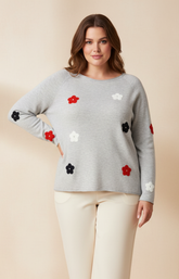 Woman wearing a gray sweater with floral patterns on a beige background