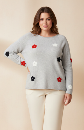 Woman wearing a gray sweater with floral patterns on a beige background