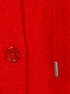 Close-up of a red buttoned knitted cardigan with a button and drawstring detail.