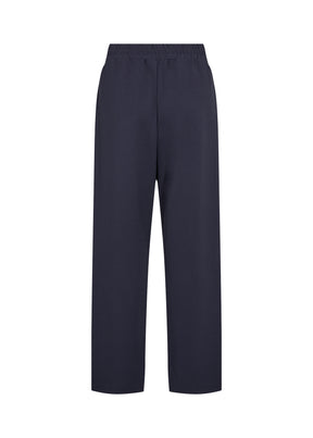 Person wearing the Wasabi Kufa Trousers in Navy, a navy wide-leg  trousers and a striped shirt on a white background 