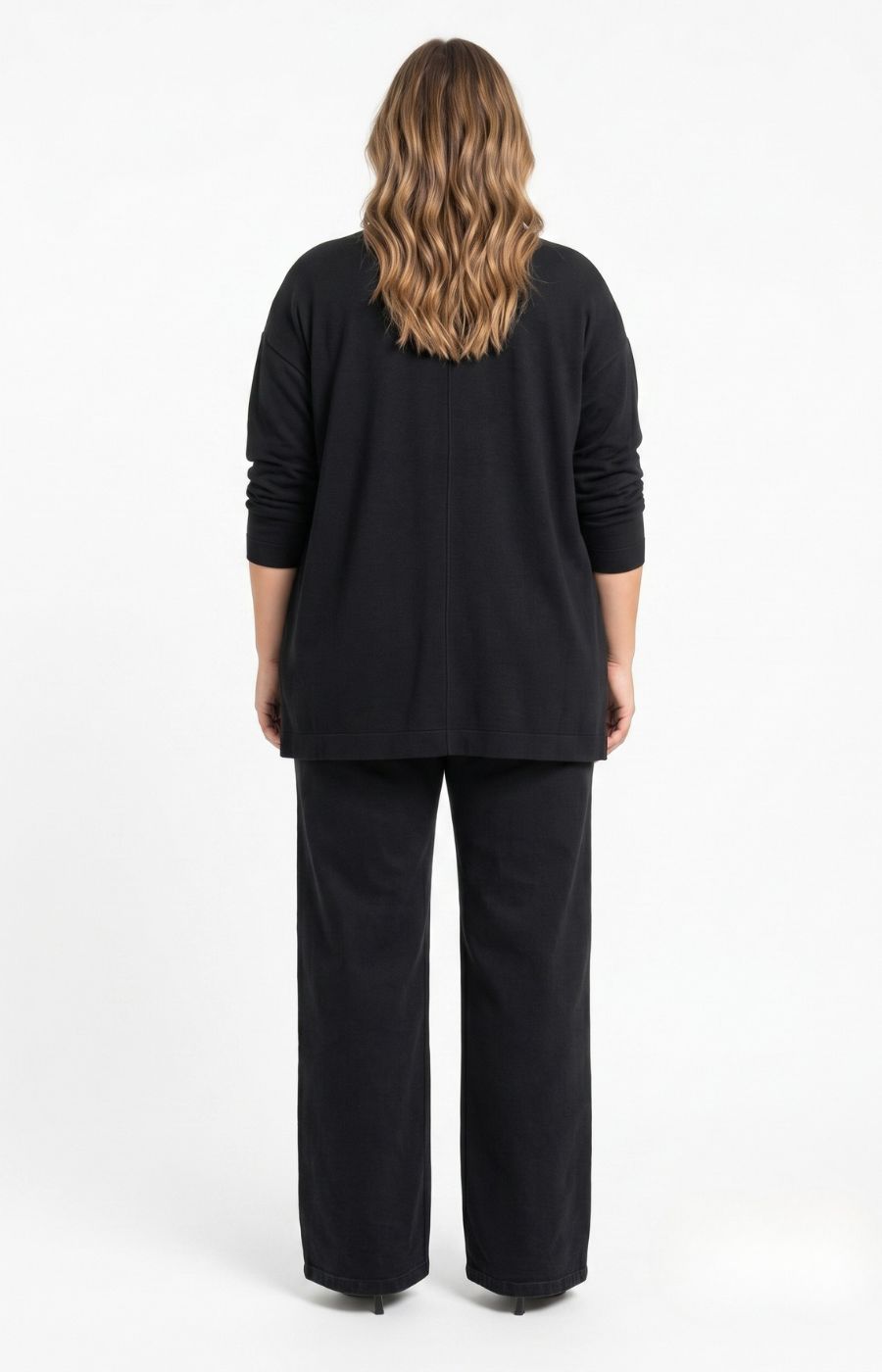 A woman viewed from the back wearing the Wasabi Sabina Pocket Cardigan in Black, a black long-sleeve top and matching black wide-leg pants against a plain white studio background. This image has been created using AI.
