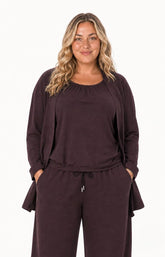 A woman modeling the Wasabi Sabina Pocket Cardigan in Brown a long line brown cardigan. This image has been created using AI.