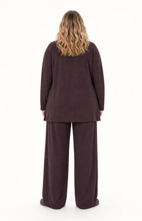 A woman viewed from the back wearing the Wasabi Sabina Pocket Cardigan in Brown a long-sleeve, long line cardigan standing against a plain white background. This image was created using AI
