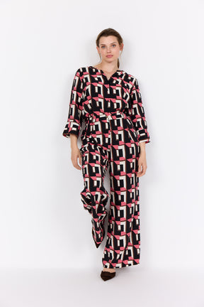 Woman wearing Wasabi Sarena Shirt in Pink with the matching trousers on a white background