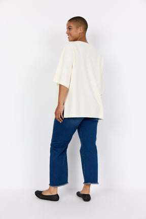 Women wearing Wasabi Sikka Jumper in Cream and blue pants on a white background