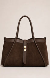 A dark brown suede tote bag with dark brown leather trim and handles, featuring a central gold-tone turn-lock clasp, photographed against a neutral light beige background.