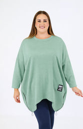 Woman wearing a Zara Sweater in Sage with a brand label on a white background