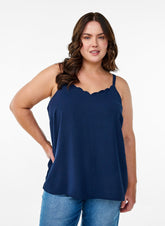 Woman wearing a navy blue sleeveless top and jeans on a white background