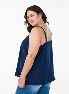 Woman wearing a navy blue top and jeans on a white background