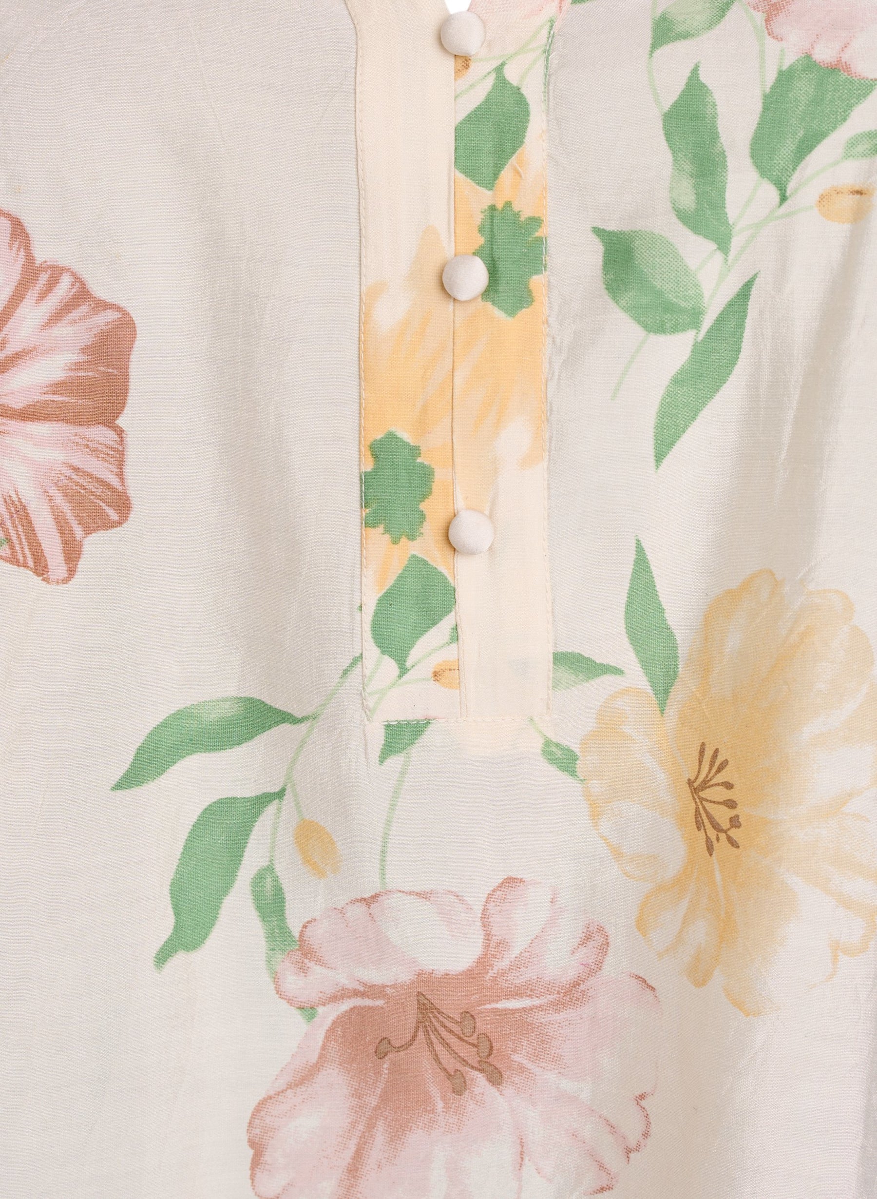 Close-up of a floral patterned fabric with pink and yellow flowers on a beige background.