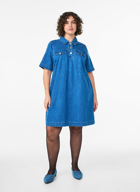 Woman wearing the Zizzi Misha Denim Dress, a blue dress with a white background