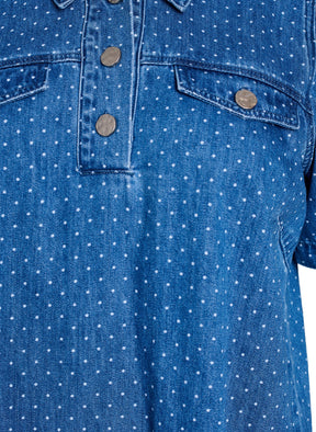 Close-up of the Zizzi Misha Denim Dress, a blue denim shirt with white polka dots and button details on faux pockets.
