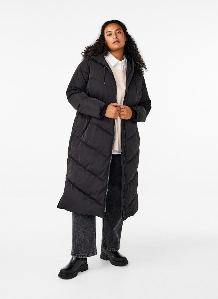 Person wearing a long black puffer coat on a white background