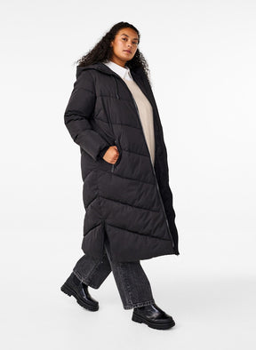 Person wearing a long black puffer coat on a white background