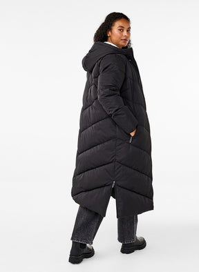Person wearing a long black puffer coat on a white background