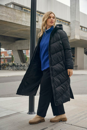 Woman wearing a long black puffer coat in an urban setting