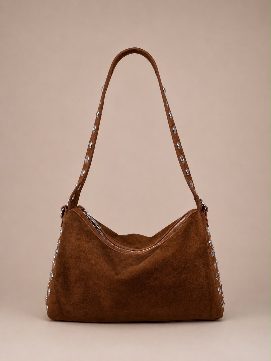 A brown suede shoulder bag with silver-tone metal studs and a matching adjustable strap, shown against a solid beige background.
