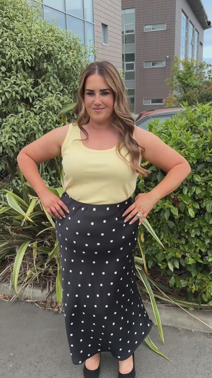 Model is wearing the Zizzi Minela Skirt in Black Polka Dot with the Kaffe Curve Carina Vest top in sunlight