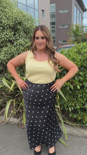 Model is wearing the Zizzi Minela Skirt in Black Polka Dot with the Kaffe Curve Carina Vest top in sunlight