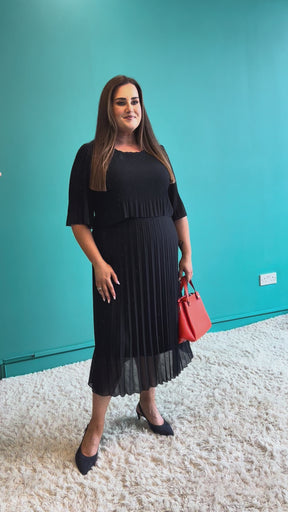 Woman wearing a navy blue dress with puffed sleeves on a teal background