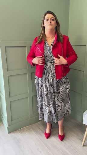 A video of a plus size woman wearing a printed midi length dress, red suede jacket and red court shoes