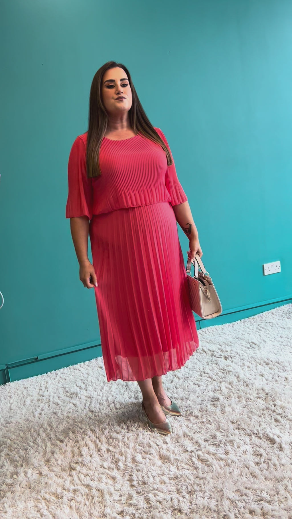 Woman wearing a coral dress with puffed sleeves on a white background