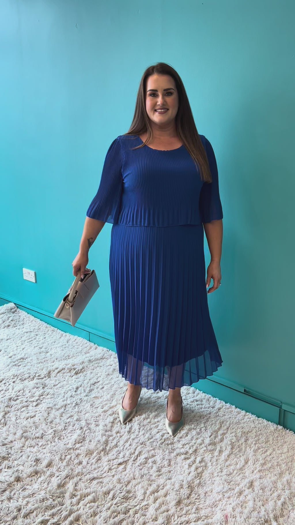 Woman wearing a blue pleated dress on a white background